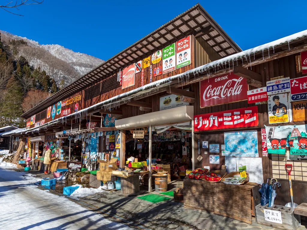 レトロな看板が並ぶ雪の日の店先（福地温泉）