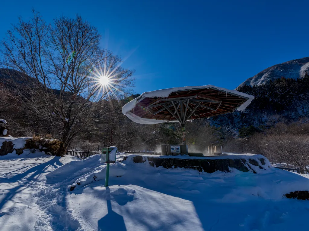 雪晴れの日差しと雪をかぶったあずまや（栃尾温泉）
